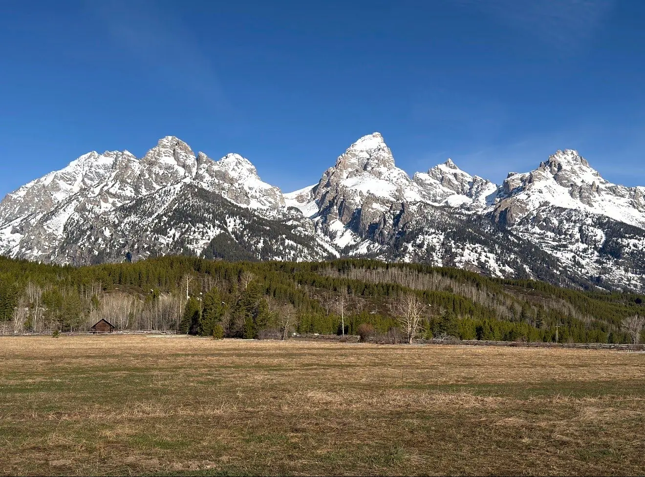 Snowy jagged peaks above a wide sagebrush plain in Grand Teton National Park.